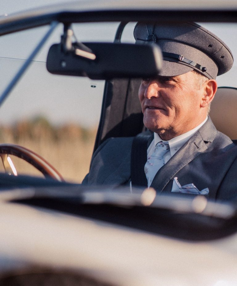 Robert James standing in chauffeur uniform beside the car